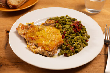 Fried boneless skinless chicken leg with green peas for garnish on plate