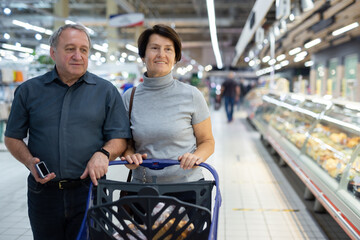 Elderly man and woman walking through a supermarket