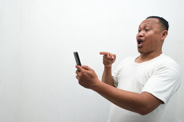 photo of the shocked expression of an Asian man looking at a mobile phone in his hand