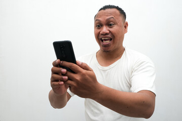 photo of the shocked expression of an Asian man looking at a mobile phone in his hand