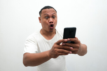 photo of the shocked expression of an Asian man looking at a mobile phone in his hand