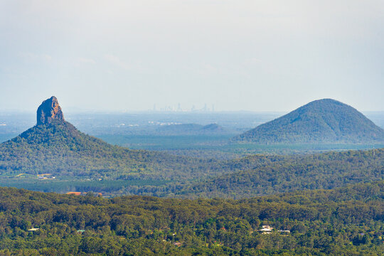 Distant view of two mountains on a flat valley floor with city skyline in the distance