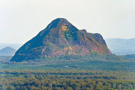 Distant view of a large mountain in a flat valley, covered in trees