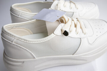 A close-up of a stylish pair of white women's sneakers with a label that has a place for your logo