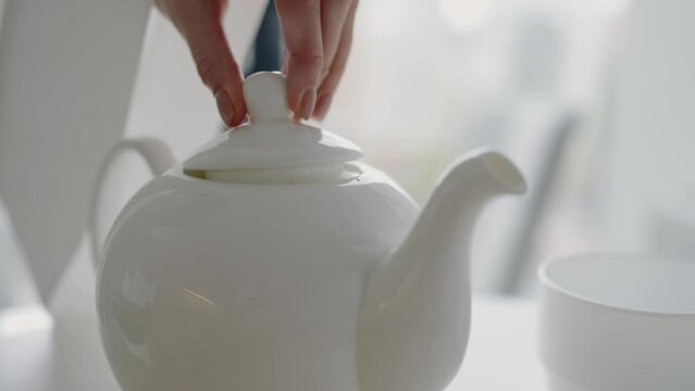 A white teapot and matching cup in a bright kitchen setting, creating a serene and inviting atmosphere for tea lovers. Perfect for concepts related to home, hospitality, and relaxation.