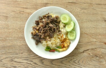fried salty slice beef meat belly with crispy shallot and chili on rice couple cucumber in plate