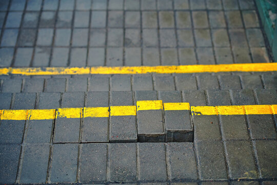 Damaged paving slabs on outdoor stairs, need for repair and maintenance to ensure safety. Stairway with damaged paving slabs. Damaged gray stairs step with yellow line. Poor quality of brickwork.