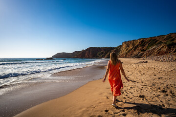 Beautiful woman walking on sunny beach Portugal, Algarve, Amado praia