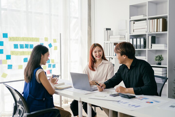 Young Professionals Collaborating in Modern Office Space with Laptops and Documents, Brainstorming Ideas and Discussing Business Plans in Bright, Contemporary Workspace