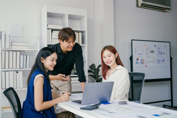Young Professionals Collaborating in Modern Office Environment with Laptops and Charts, Engaging in Productive Discussion and Teamwork