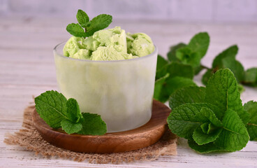 Mint ice cream or sorbet in a glass on a white wooden background.
