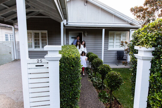 A zoomed out view of a family of four walking out front door of their home