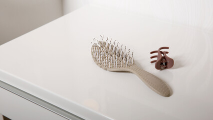 Close up of used hair brush on white table, hair loss and head skin hygiene at home concept