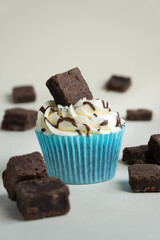 Brownie vanilla cupcake with chocolate drizzle on white background with brownie slices