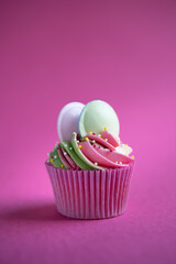 Delicious rainbow cupcake on pink background with flying saucers and sprinkles