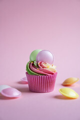 Delicious rainbow cupcake on pink background with flying saucers and sweets