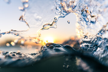 Macro shot of splashing water in orange sunset half underwater © Jens