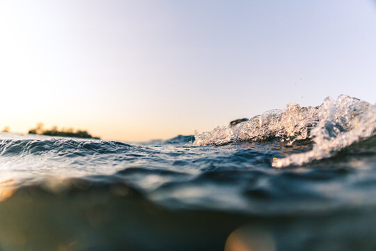 Surge of waves in orange sunset conditions close to water surface