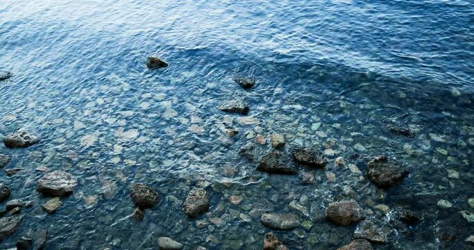 Il fluttuare del mare calmo a riva con rocce e onde con schiuma 