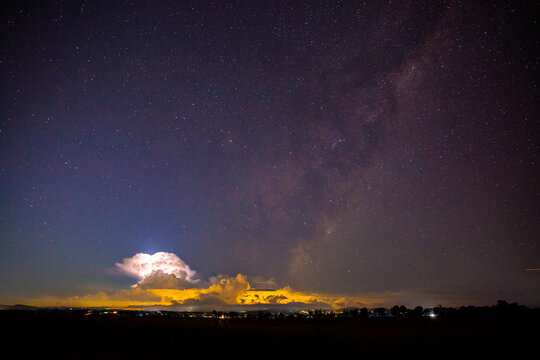 milky way with a storm cloud lit up by lightening in the frame