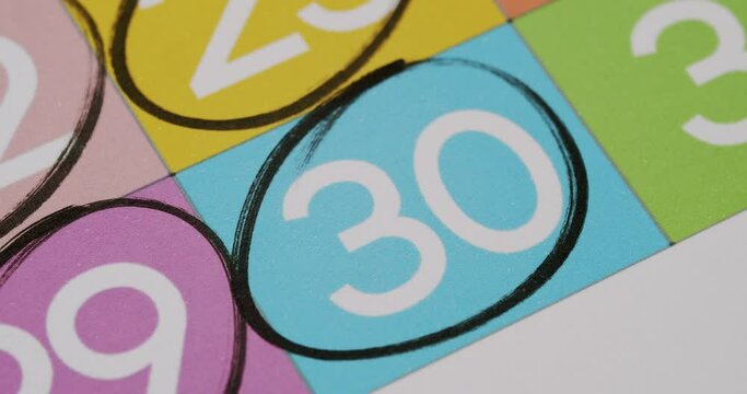 Macro shot of the number 30 circled on a vibrant bingo game board, highlighting colorful squares. Close-Up of Number 30 Circled on Colorful Bingo Game Board