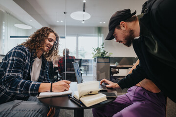 Two young men engaged in business discussion, analyzing data on a laptop in a brightly lit modern office space.