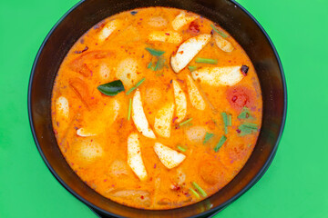 Spicy sour soup Tom Yam on a green background. Thai cuisine