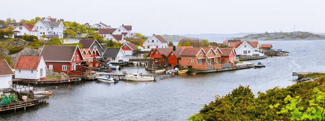 Charming Red and white cottages by the waterfront, with boats docked along the pier. Cold...