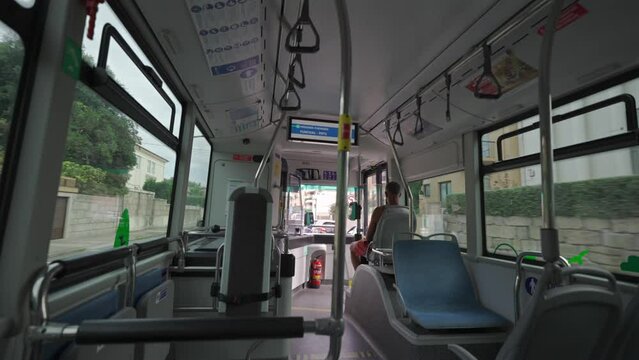 Interior inside city bus during trip to Porto, Portugal in summer. Theme urban public transportation in Opoto, Portuguese. View from passenger seats to interior of fast moving bus. Coach saloon. 