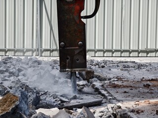 A hydraulic hammer breaking concrete at a construction site
