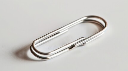 A single silver paperclip on a white background. The paperclip is lying flat, with the top loop facing the camera.
