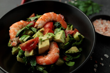 Salad of king prawns, avocado, cucumber, tomato and herbs. Black background