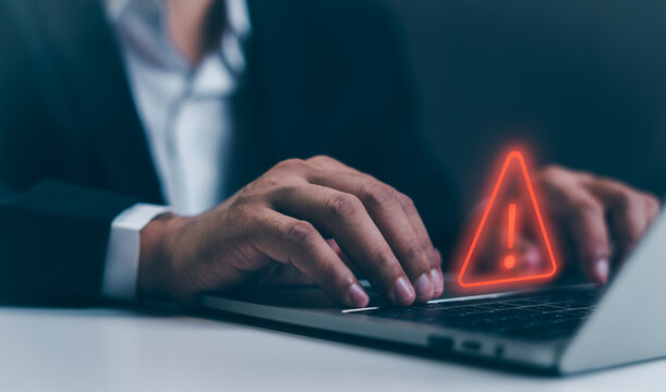 A Businessman developer using laptop computer with triangle caution warning sign for notification error and maintenance concept, network security, computer virus detected, personal data protection.