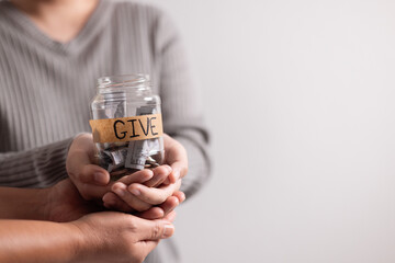 Woman held jar filled with cash with words in bold lettering urging people to donate money,...