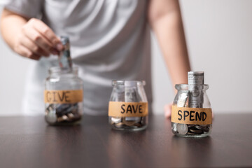 Manage her money wisely, she used glass jar to save coins, deciding when to spend or save as part of her business strategy before depositing in bank. give, money, save, spend, coin, business, jar.