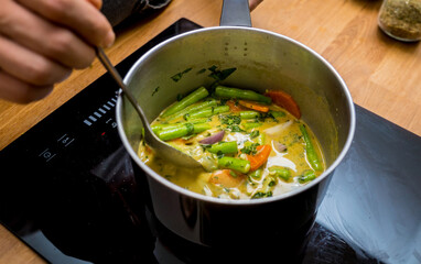 Chef at the kitchen preparing green curry with herbs and rice