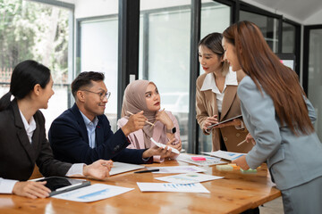 Asian business group discussing graph work at the office..