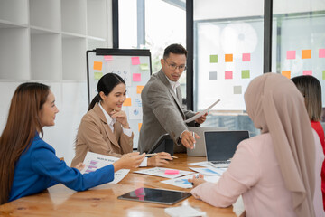 Asian business group discussing graph work at the office..