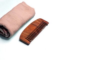 Wooden comb with a folded towel on a white background for texts and posters