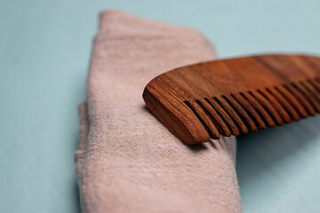 Extreme close-up of a Wooden comb and a properly folded towel kept on a sky blue background