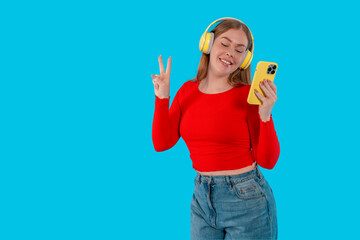 Young Woman Wearing Red Top and Jeans Enjoys Music With Headphones and Smartphone