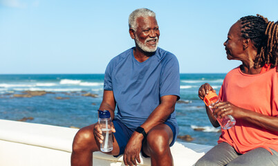 Elderly couple enjoying a seaside break and staying hydrated
