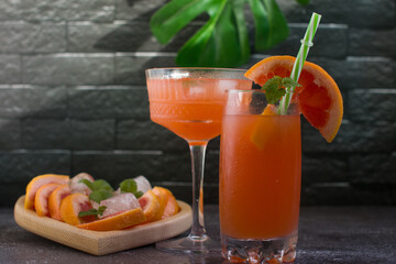 Grapefruit drink in a glass with a straw, mint and ice. Refreshing drink, freshly squeezed refreshing juice