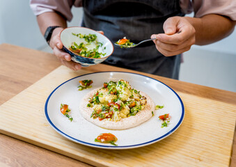 Chef at the kitchen preparing bean porridge with cauliflower and vegetables