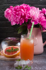 Grapefruit drink in a glass with a straw, mint and ice. Refreshing drink, freshly squeezed refreshing juice