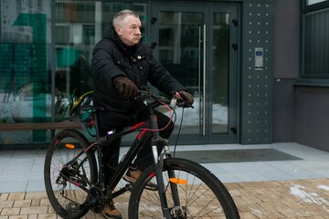 Obraz premium European elderly man leading a healthy lifestyle and riding a bicycle in winter
