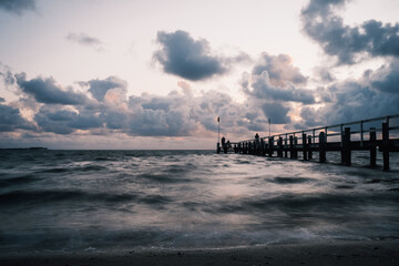 Fototapeta premium Glatte Wellen und ein alter Steg in der Nordsee auf Insel Föhr