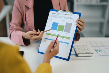 Business Meeting with Financial Analysis on Clipboard, Two Professionals Discussing Savings Goals, Analyzing Data with Calculator, Office Environment, Teamwork, Financial Planning, Business Strategy