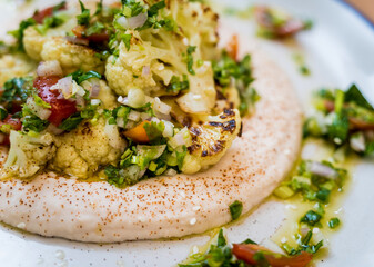 Tasty bean porridge with cauliflower and vegetables on white plate
