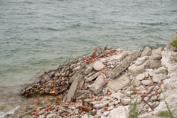 construction waste dumped at the edge of the lake and undergoing a process of weathering and erosion